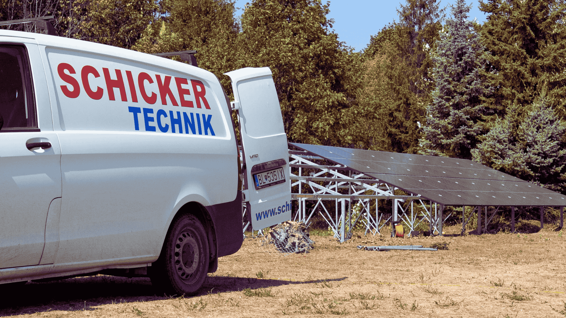 Lieferwagen in der Nähe von Solarmodulen in einem bewaldeten Gebiet