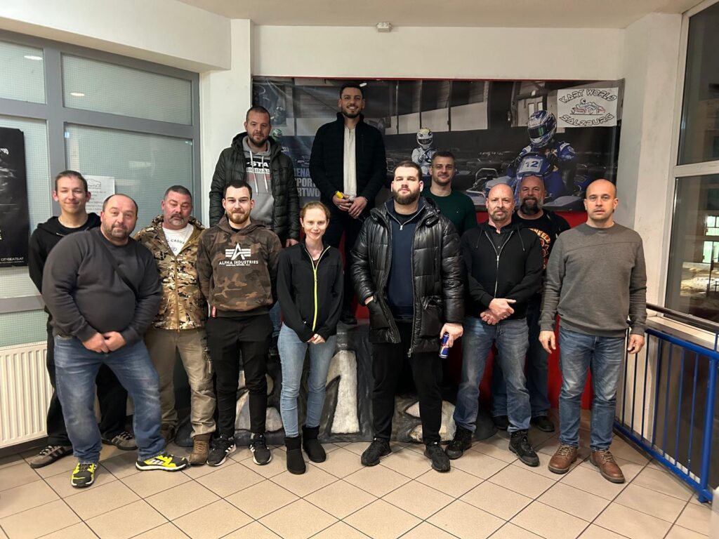 Gruppe von Menschen posiert in Kartbahn-Umgebung.