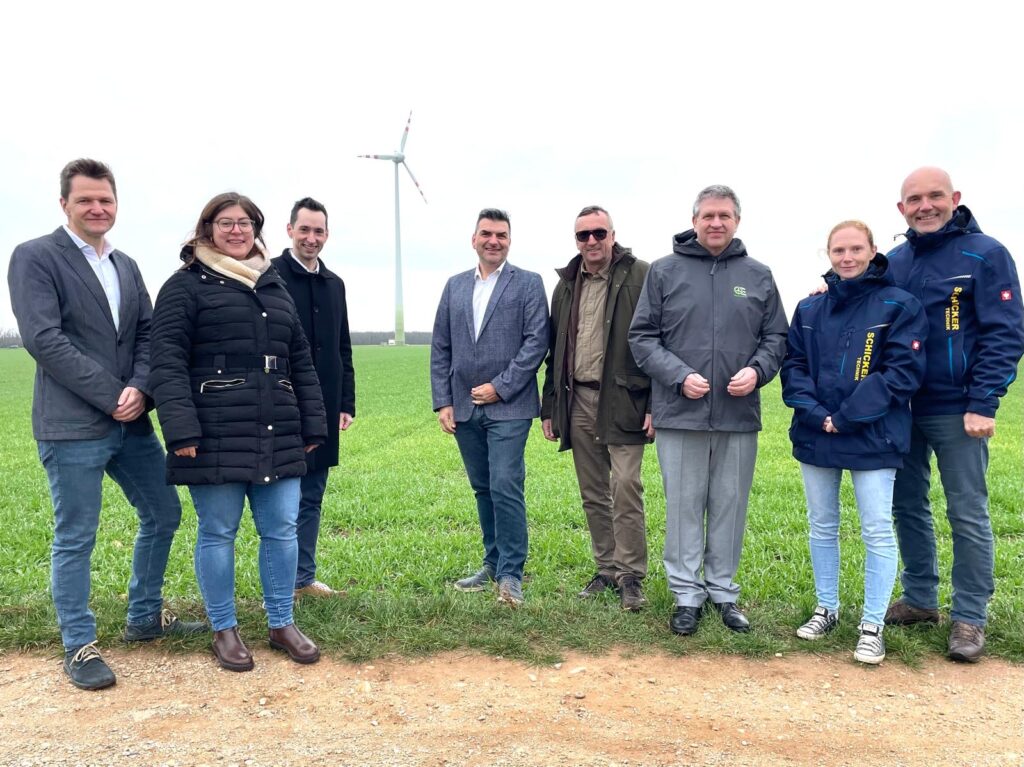 Menschen vor einem Windrad auf einem Feld